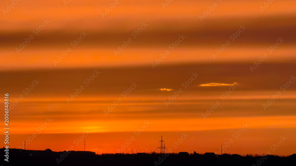 Obraz premium Orange sunset sky over horizon with silhouettes and clouds