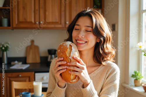 Smiling young woman sitting in a kitchen holding a freshly baked loaf of bread, warm cozy atmosphere, home cooking and comfort food concept.
