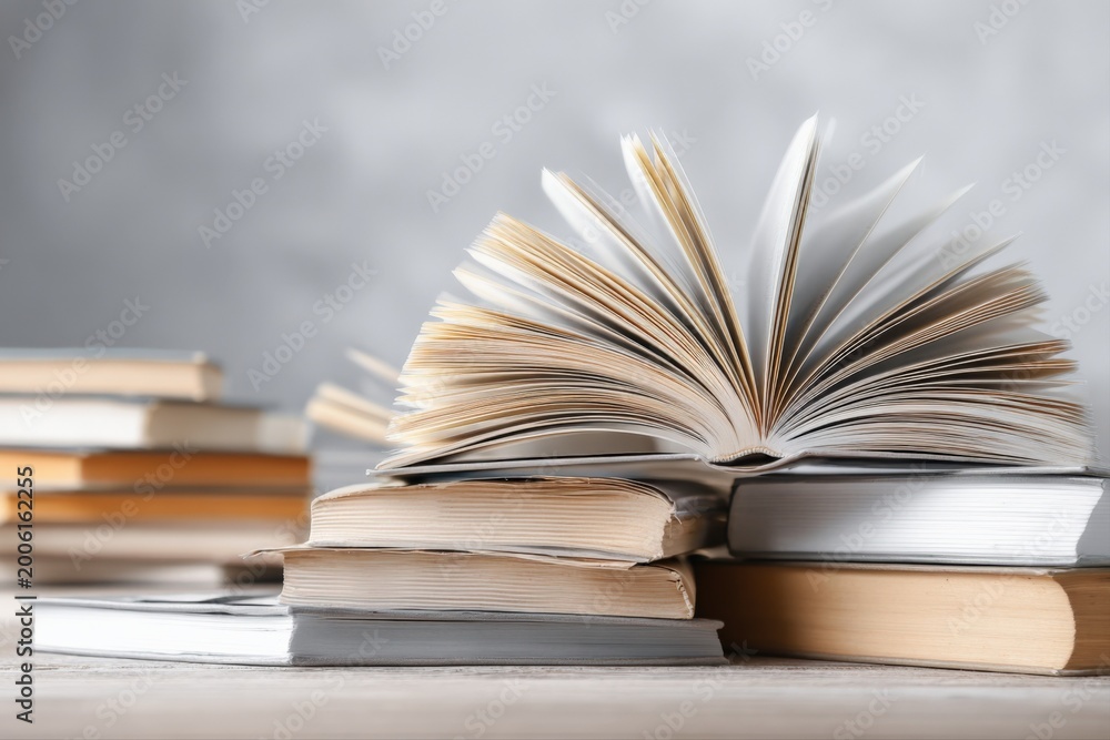 Fototapeta premium Open and closed books stacked on a table, symbolizing knowledge, learning, and reading