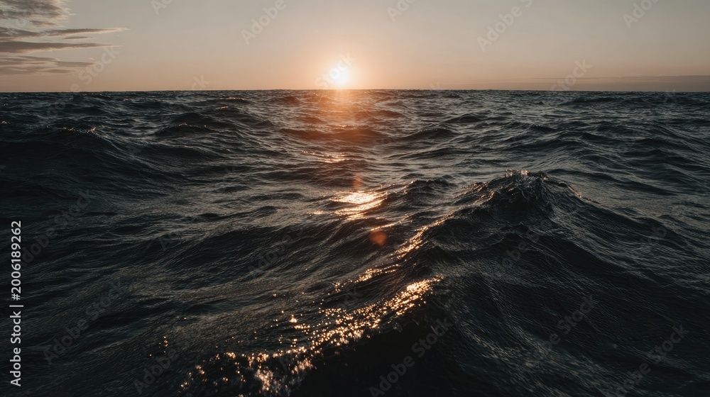 Obraz premium Brilliant sunlight reflects upon dark, restless ocean waves during twilight.