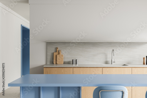 Modern minimalist kitchen interior with blue island, light wood cabinetry, soft grey backsplash and clean architectural lines. 3D Rendering
