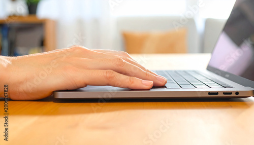 Typing Hand on a Laptop: The image captures a close-up perspective of a hand resting on a laptop keyboard, ready to engage in tasks, representing digital interaction and modern workflow.
