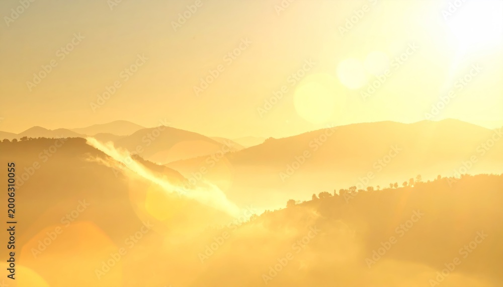 Fototapeta premium Golden sunrise over misty hills, soft light flooding landscape, creating a serene and warm atmosphere