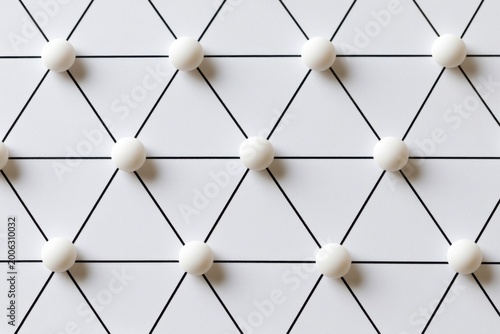 Network nodes arranged in a grid pattern with white spheres connected by black lines on a flat surface, illustrating a geometric design concept