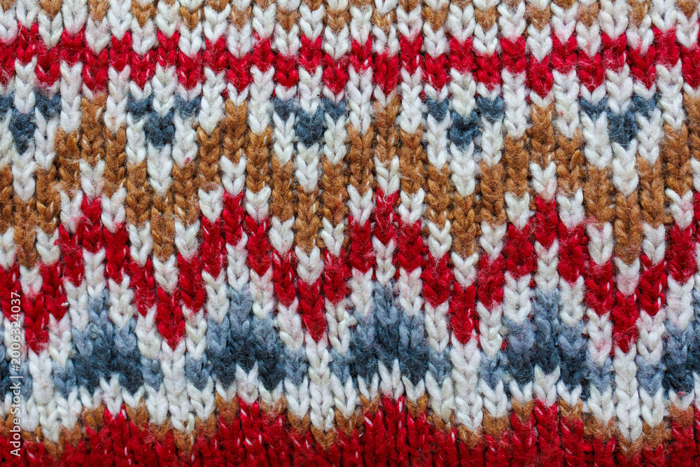 Obraz premium Traditional knitted pattern texture with red white and brown ornament, wool fabric close up