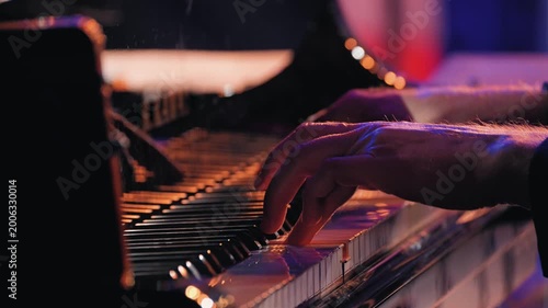 Close-up of a musician's hands playing the piano keyboard during a jazz performance on stage. A detailed close-up a professional pianist's hands on piano keys