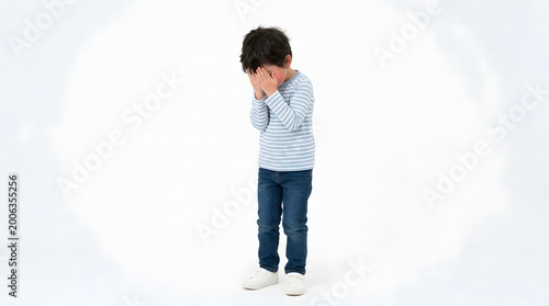 Young boy covering his face with his hands in distress or sadness, isolated on a white background, conveying emotions of unhappiness or worry