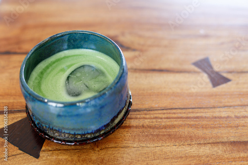 Cup of fresh matcha tea, green tea on wooden table.