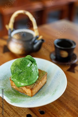 Scoop of matcha tea, green tea ice cream on toasted bread on wooden table.