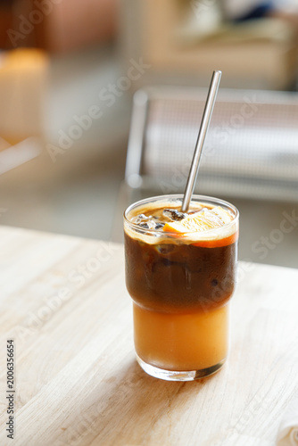 Cup of creation black coffee drink and orange juice on wooden table by the window.