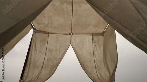 Low angle view inside of a light canvas tent with the opening against a cloudy sky