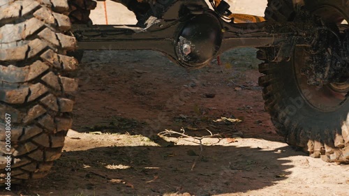 A close-up of a muddy SUV tire and suspension. Mud covers the large treads and wheel rim. Concept of motorsports, adventure, and extreme driving