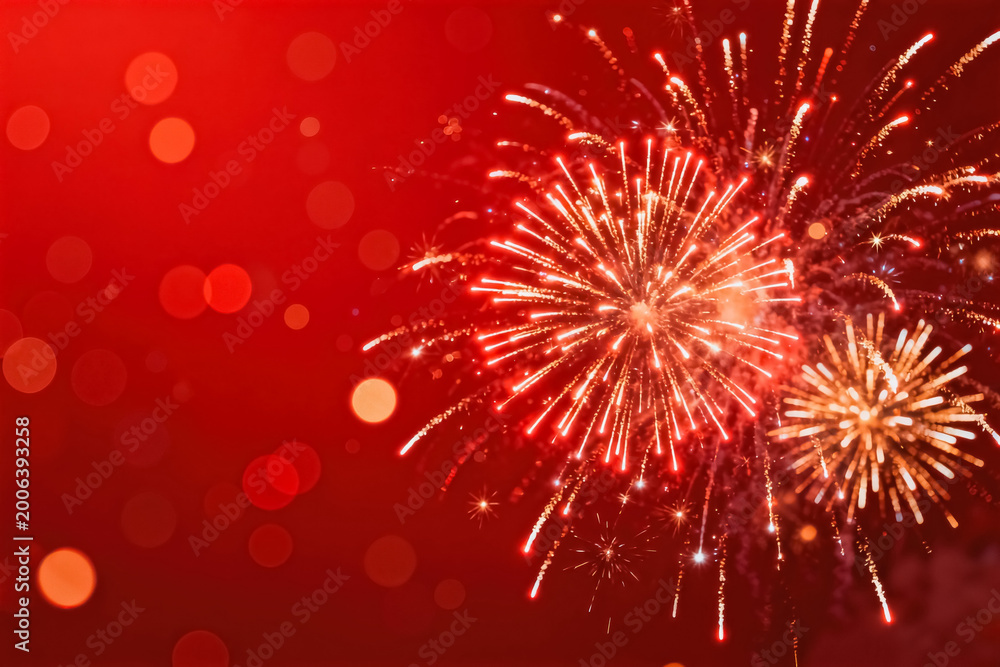 Obraz premium This is a festive red background with sparkling fireworks displays, with soft bokeh light effects creating a warm celebratory atmosphere.
