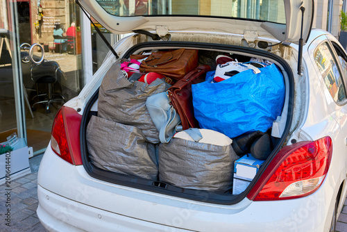 Foto Open trunk of a white car stuffed with bags of clothes, shoes, and luggage