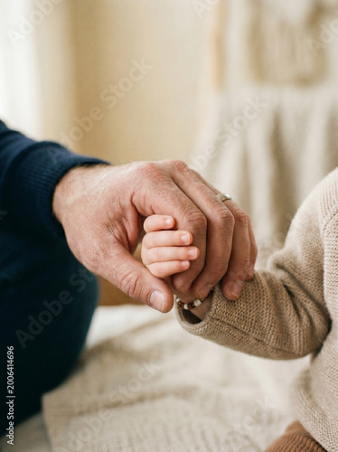 Close up of a father holding his baby's tiny hand, showing love, protection, and a strong family bond.