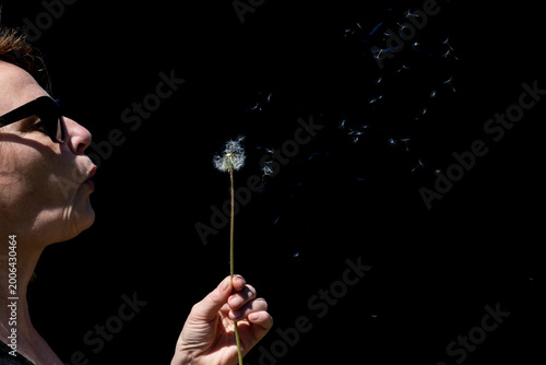 A woman makes dandelion spores fly by blowing on them