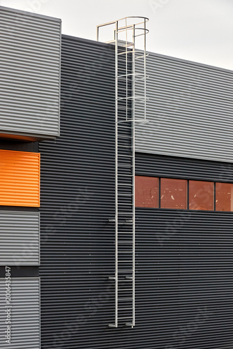 Εκτύπωση καμβά Architectural facade with orange cladding corrugated metal panels, industrial vertical ladder with a safety cage or crinoline, large glass window