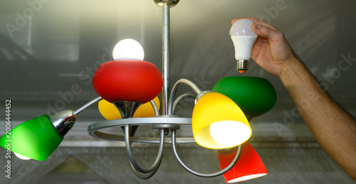 Slika na platnu Switch from outdated lighting to LED shown as man fixes lamp