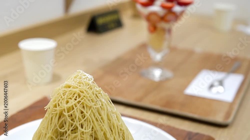 絞りたて生モンブランのクローズアップ 背景にいちごパフェのあるカフェの風景