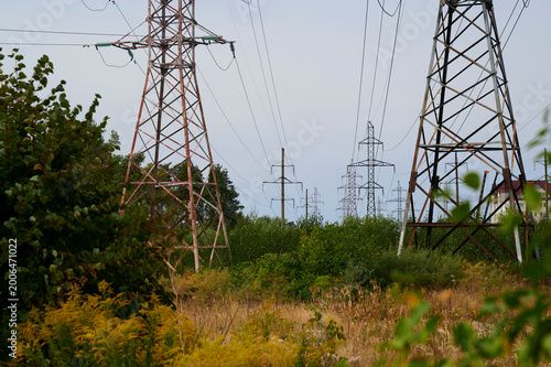 Schilderij op canvas Power lines stretch across the landscape under an open sky near a quiet field