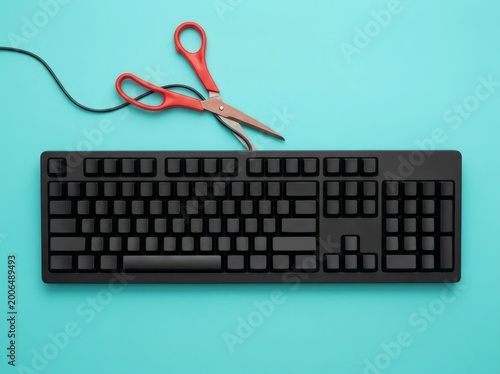 Black Computer Keyboard With Red Scissors On Turquoise Background.