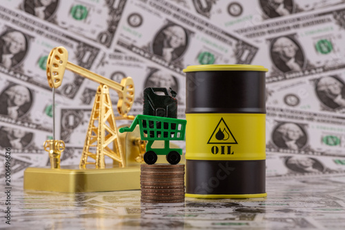 Fotografie A gasoline can and a gold oil pump against a backdrop of a $1 bills