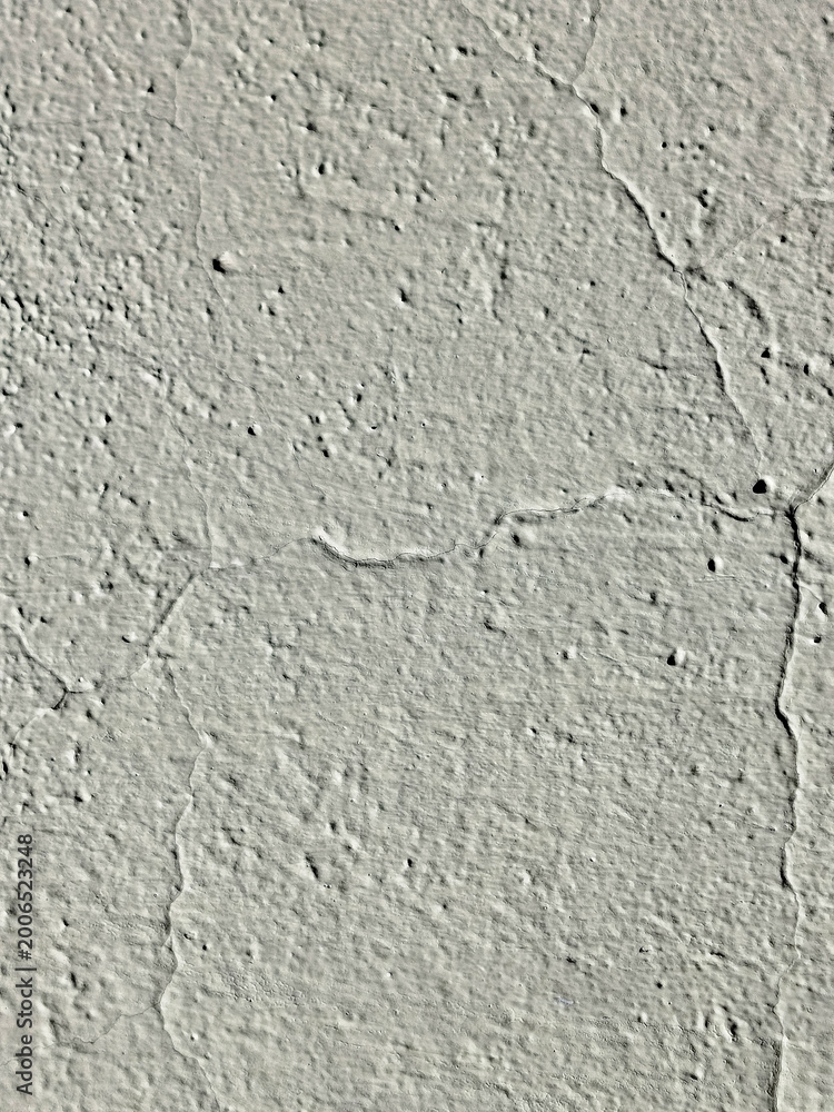 Fototapeta premium Textura de muro con estuco gris y grietas marcadas sobre superficie rugosa