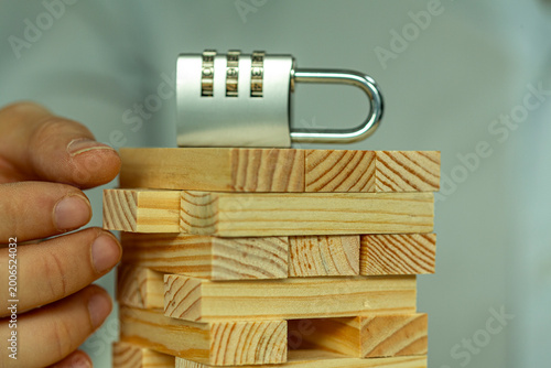 Security concept with a combination lock balanced on a unsteady tower of wooden blocks.