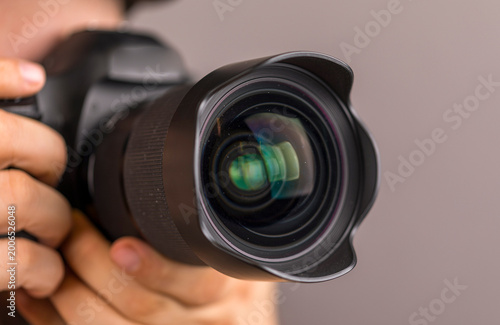 Cuadro en lienzo Close-up of a photographer holding a camera, focused on the lens