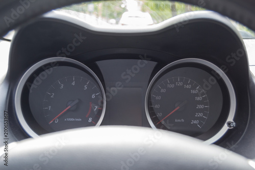 Car Dashboard with Speedometer and Tachometer Behind Steering Wheel