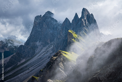 Seceda, Dolomites, Italy—lush green alpine ridge in South Tyrol with rising mist clouds from below. Dramatic overcast mountain landscape in the Alps, scenic hiking and travel destination.