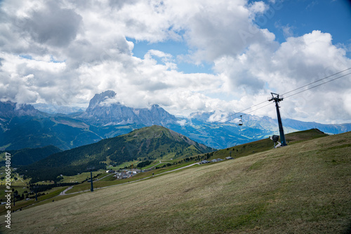 Ortisei, Val Gardena, Italy—alpine village in South Tyrol with distant Dolomite peaks rising above lush green valleys. Scenic Alps landscape with clear mountain views and travel appeal.