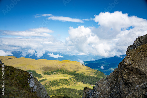 Ortisei, Val Gardena, Italy—alpine village in South Tyrol with distant Dolomite peaks rising above lush green valleys. Scenic Alps landscape with clear mountain views and travel appeal.