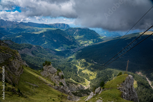 Ortisei, Val Gardena, Italy—alpine village in South Tyrol with distant Dolomite peaks rising above lush green valleys. Scenic Alps landscape with clear mountain views and travel appeal.