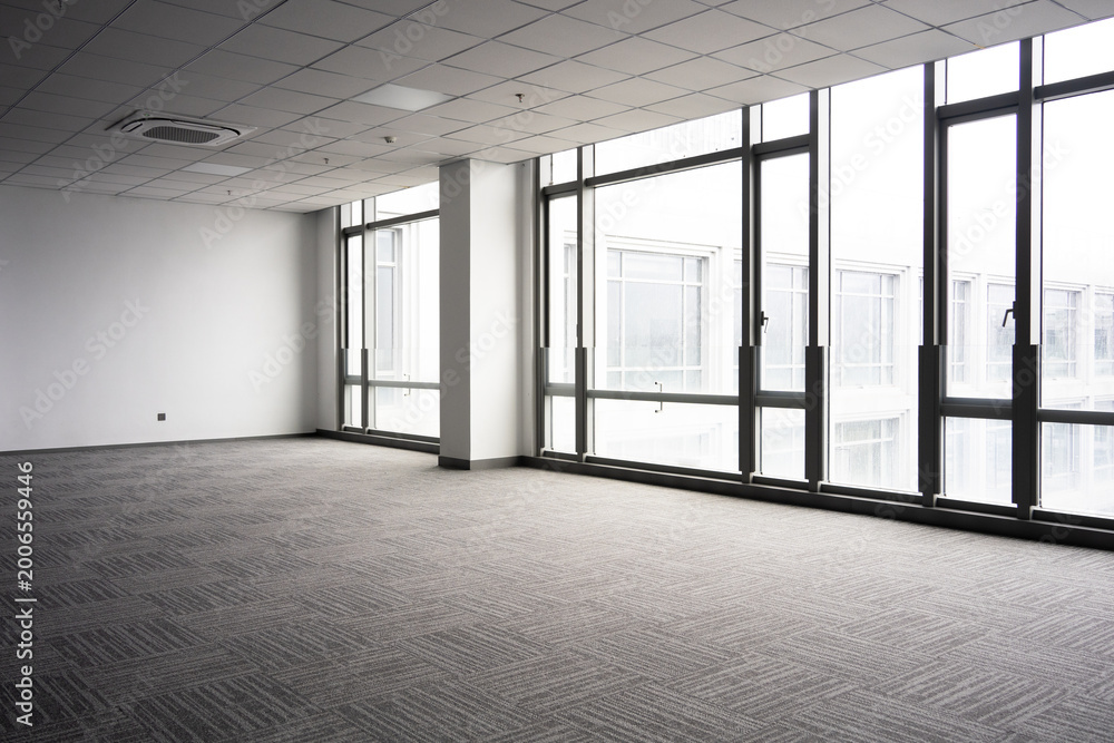 Naklejka premium Spacious modern office interior with floor-to-ceiling windows and gray patterned carpet