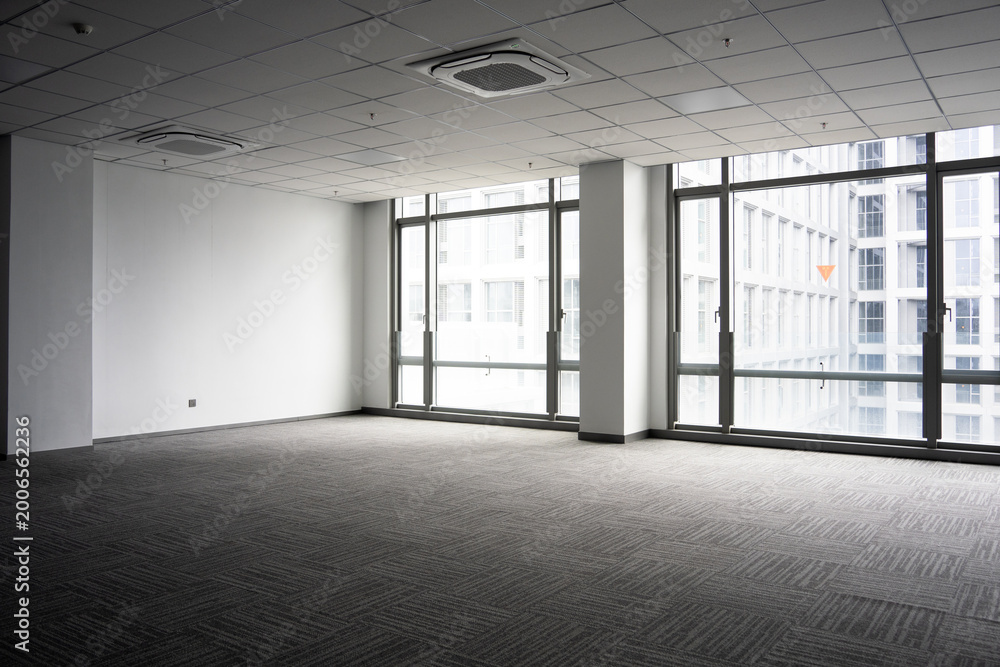 Fototapeta premium Spacious modern office interior with empty space, gray carpet, ceiling panels, and large glass windows