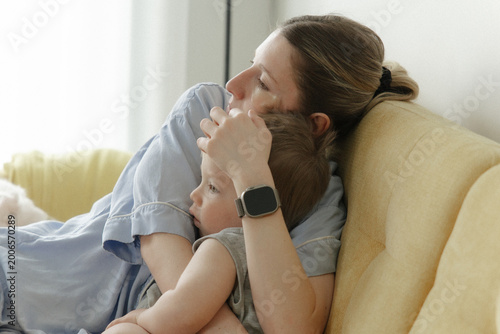 Mother hugging child on sofa at home, tender family moment, parenting, love and emotional support