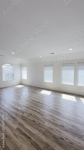 Empty vacant open concept living room and kitchen with wooden floor white walls with stainless steel appliances and granite countertops. 
