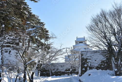 Snowy path leading to Aizu-Wakamatsu Castle under clear blue sky