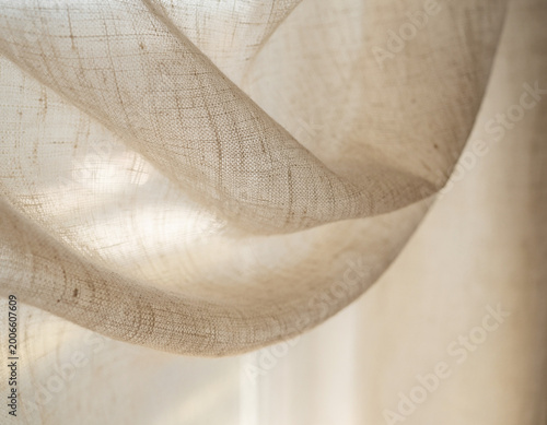 Macro view of luxurious linen curtain fabric blowing in gentle breeze with soft diffused lighting and elegant textile texture for interior design inspiration