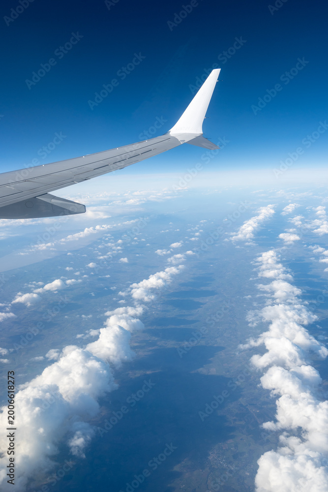 Obraz premium Airplane wings extend above white clouds, providing clear view of atmospheric layers and sense of altitude during the flight, air transportation