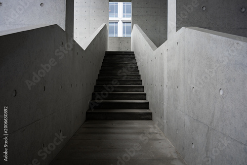 фотографія Concrete staircase interior with geometric structure and dramatic light and shad