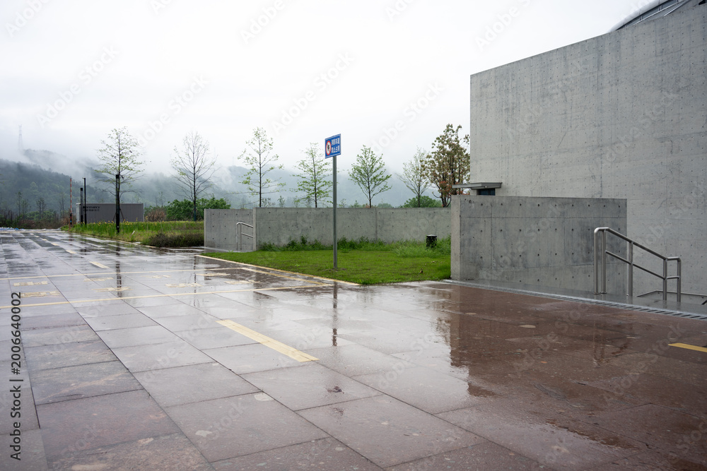 Fototapeta premium Wet pavement in a modern architectural plaza after rain with distant mountains and fog