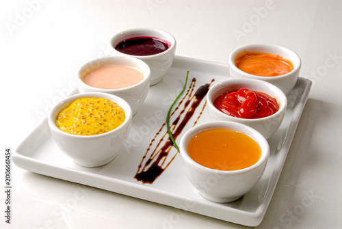 Jars of mustard sauces, ketchup, mayonnaise, honey, hot sauce on a white background