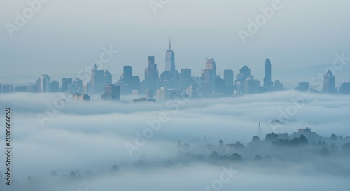 Aerial view of a foggy cityscape with skyscrapers and buildings emerging from the misty atmosphere in a landscape.