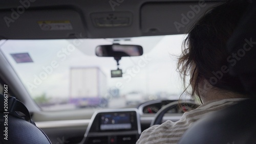 Slika na platnu A woman driver navigates through highway traffic during her daily commute, viewed from the back seat of the car with a dashcam recording the journey ahead
