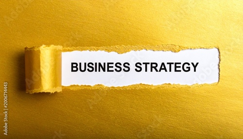 Golden ripped paper dramatically reveals the crucial message BUSINESS STRATEGY against a white background.