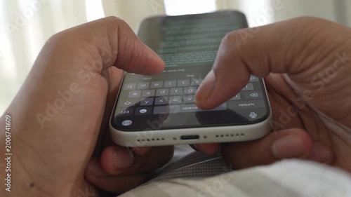 Close-up macro shot of anonymous male hands typing and chatting on a smartphone, fingers tapping a touchscreen keyboard while sending text messages in a modern digital environment. Unrecognizable pers