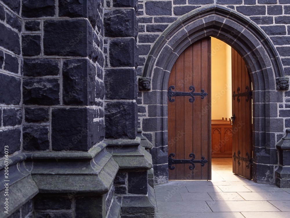Fototapeta premium Complete heavy arched wooden church door with a stone wall copy space