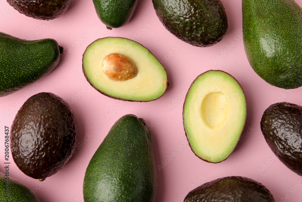 Fototapeta premium Whole and cut avocados on pink background, flat lay